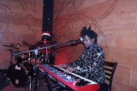 a man playing a keyboard in front of a drum set