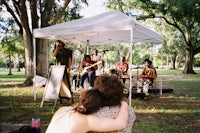a group of people sitting under a tent in a park
