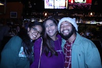 three people posing for a photo at a bar