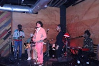 a group of people playing music on stage in front of a wall