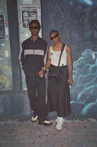 a man and woman standing in front of a graffiti covered wall