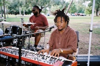 a man with dreadlocks playing a keyboard in a park