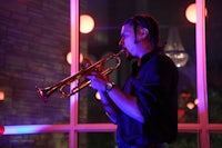 a man playing a trumpet in front of a window