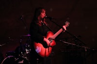 a woman playing an acoustic guitar in front of a microphone