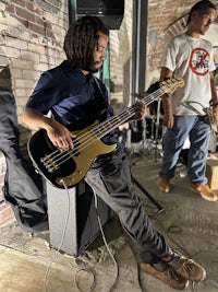 two men playing bass in a brick building